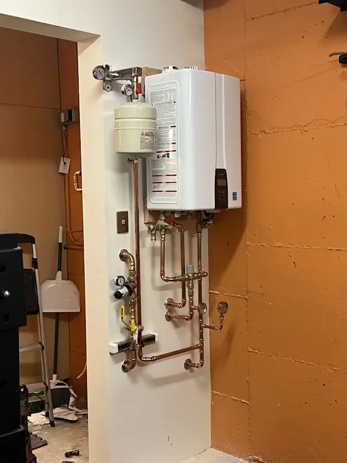 Plumbing technician inspecting water heater connections in Aumsville